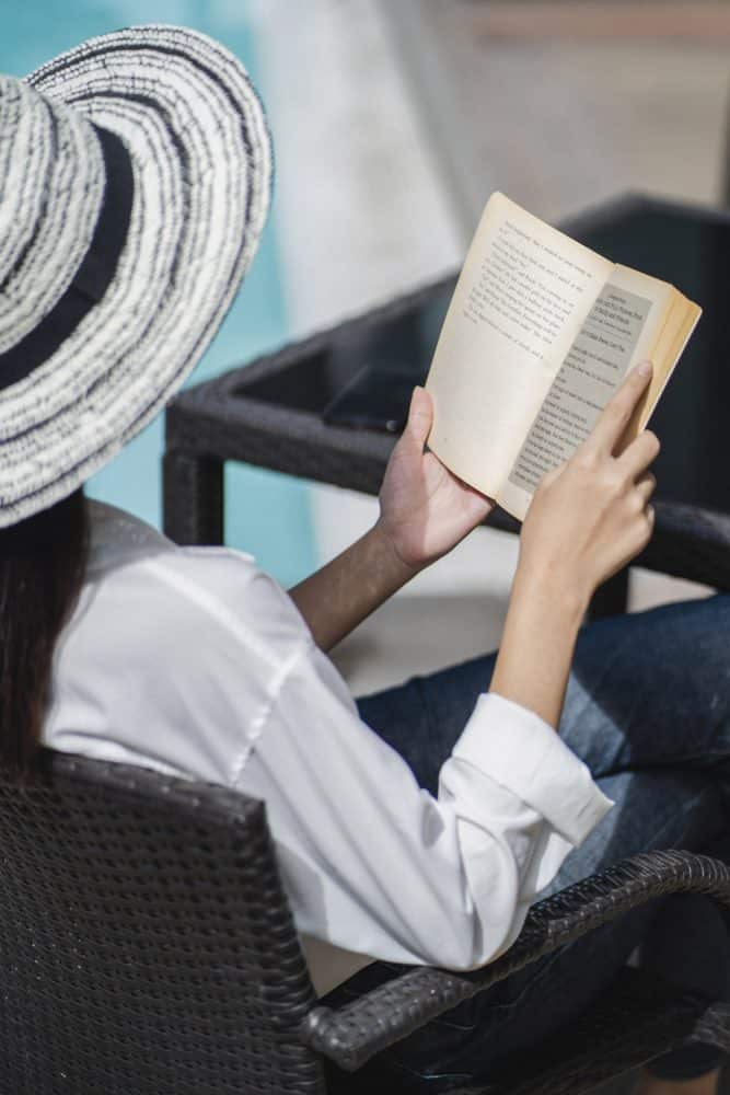 Woman reading a book outside with a sun hat near goddard point hope sc rentals pexels-armin-rimoldi-5269616