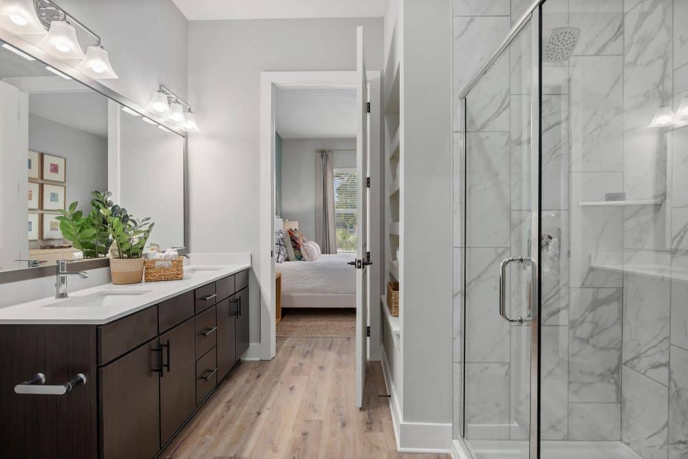 Model bathroom of our apartments in Charleston, SC featuring dual sink vanity, built-in shelving and glass shower.