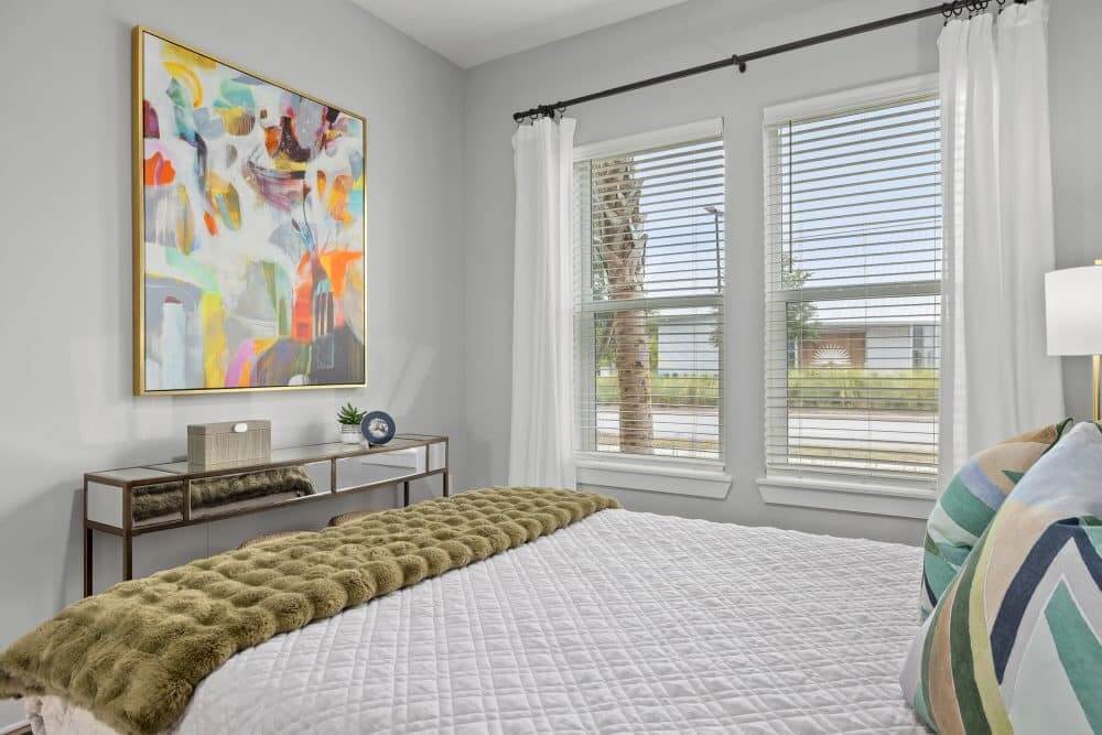 Model bedroom of our apartments in Charleston, SC featuring wood grain flooring and large windows.