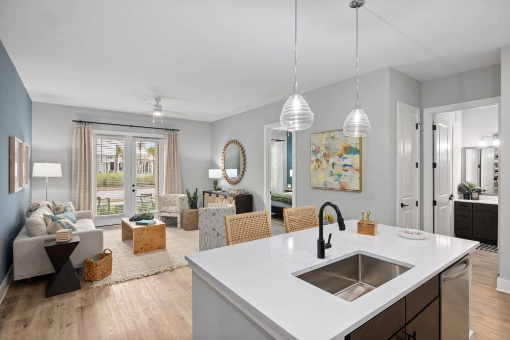 Model living room and kitchen at our apartments in Charleston, SC, featuring wood grain flooring and a kitchen island.