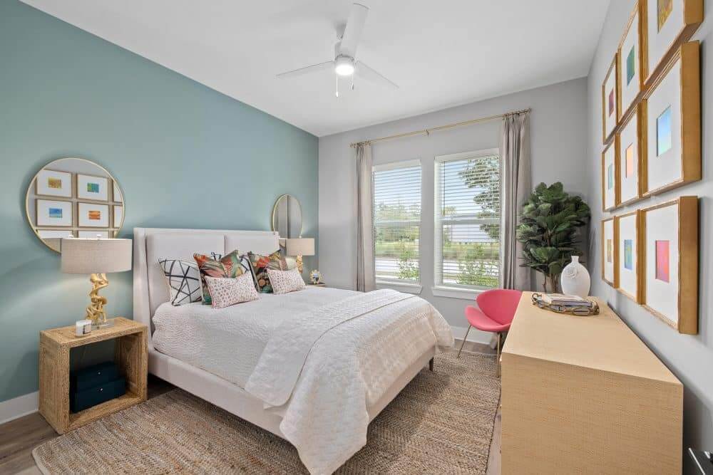 Model bedroom of our apartments in Charleston, SC featuring wood grain flooring and large windows.